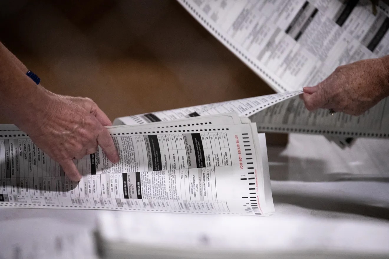 Hand count image from Arizona Republic The hands of two white humans are shown sorting through paper ballots.