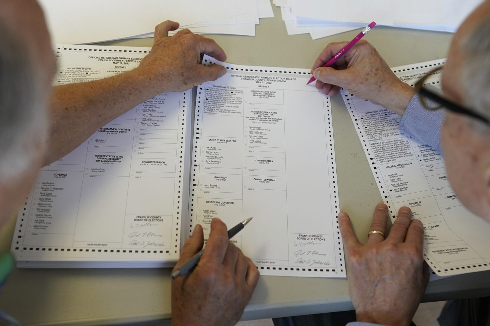 Lycoming hand count Two workers holding pencils handle a ballot