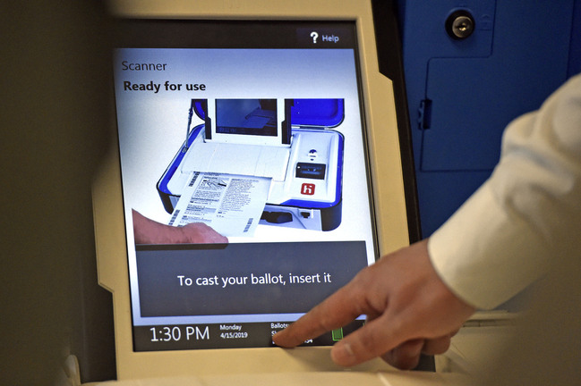 Verity_Scan_Screen_650 White touch screen reads "Scanner. Ready for use. To cast your ballot, insert it" with a timestamp of 1:30 pm. White hand touches bottom of screen.